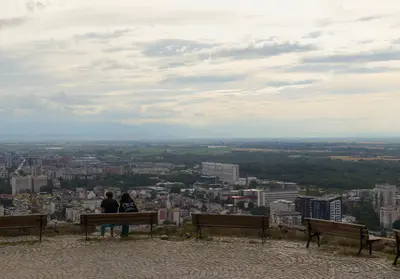 Жена и момиче, седнали на пейка, на върха на Младежкия хълм в Пловдив.